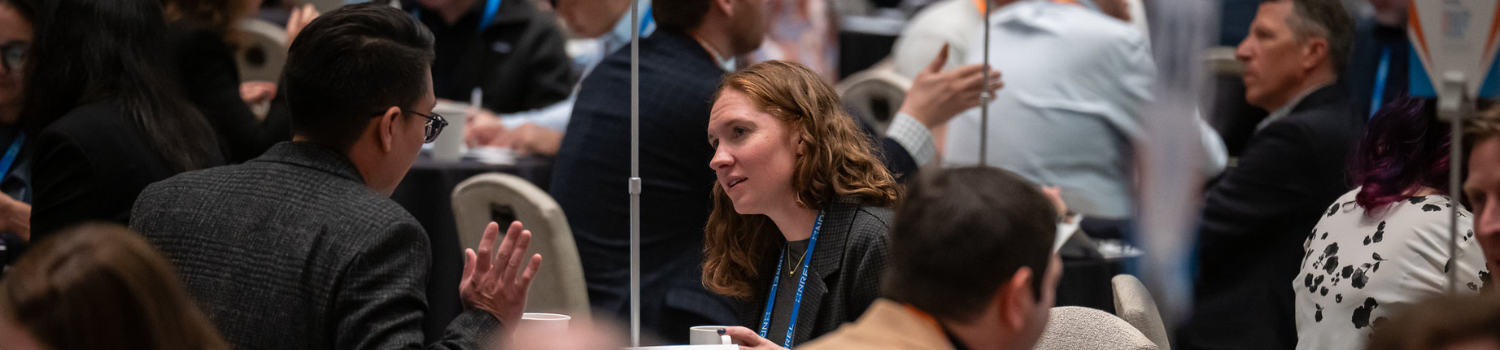 two people talk in a crowded room