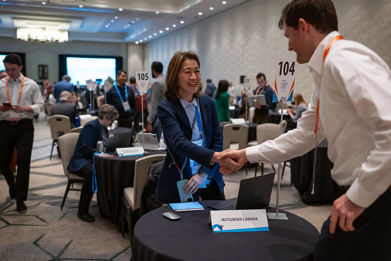 Two people shake hands in crowded room