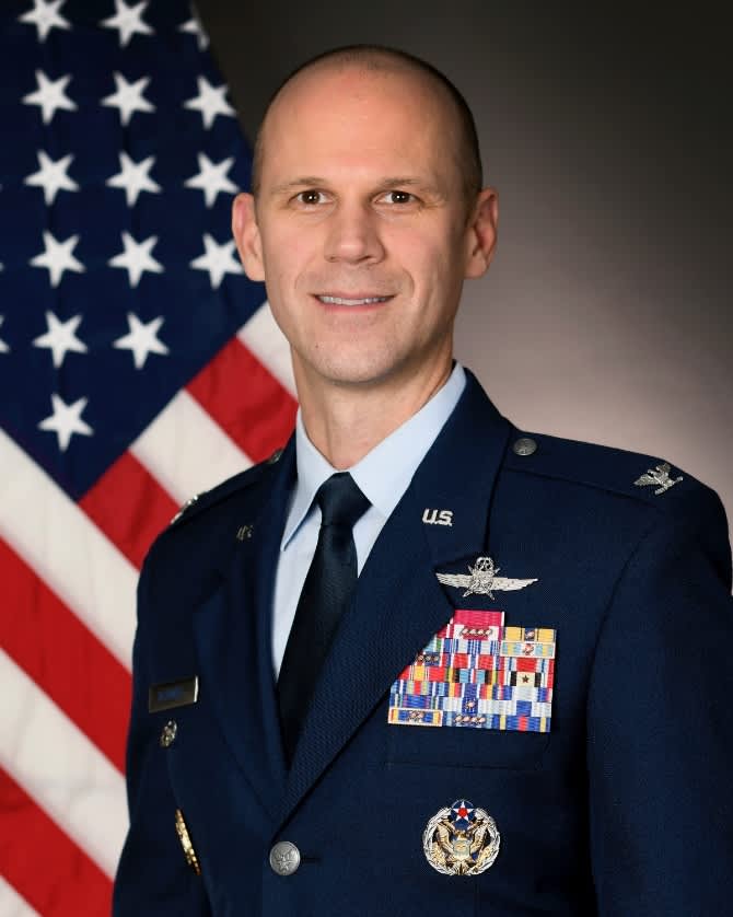 A man in uniform sitting in front of an American flag